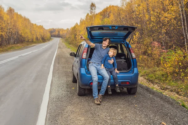 Dad and son are resting on the side of the road on a road trip. Road trip with children concept
