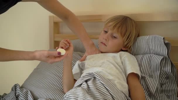 Superslowmotion lövés egy beteg kisfiú egy ágyban. Anya súrolja a fiúk mellkasi kenőcsöt illóolajok. Gyermekinfluenza koncepció — Stock videók