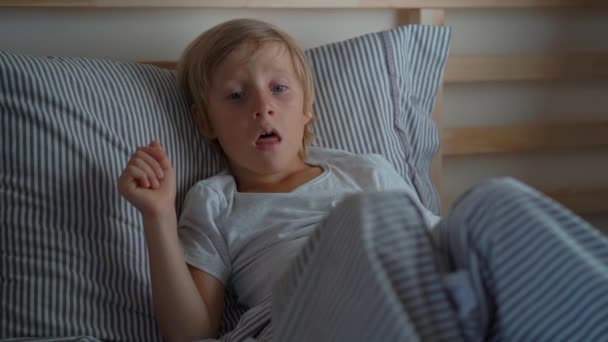 Beteg kisfiú egy ágyban. Superslowmotion shot egy fiú köhögő az ágyban. Gyermekinfluenza koncepció — Stock videók