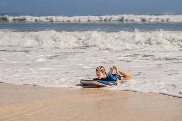 Fröhlicher kleiner Junge, der im Urlaub Spaß am Strand hat, mit Boogie Board — Stockfoto