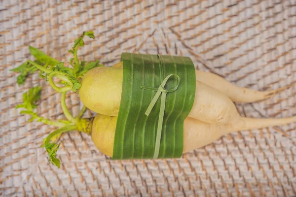 Eco-friendly product packaging concept. Vegetables wrapped in a banana leaf, as an alternative to a plastic bag. Zero waste concept. Alternative packaging