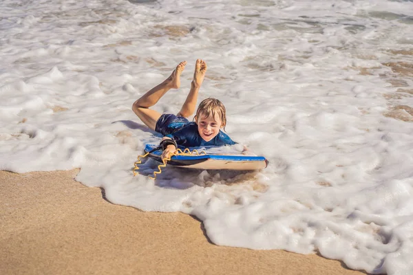 浜の休暇は、ブギー ボード上で楽しんで幸せな少年 — ストック写真