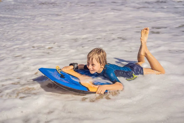 Glad ung pojke att ha kul på stranden på semester, med boogie board — Stockfoto
