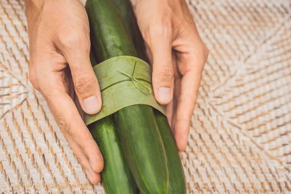 Eco-friendly product packaging concept. Cucumber wrapped in a banana leaf, as an alternative to a plastic bag. Zero waste concept. Alternative packaging