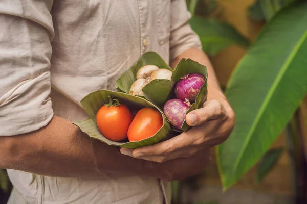 Eco-friendly product packaging concept. Vegetables wrapped in a banana leaf, as an alternative to a plastic bag. Zero waste concept. Alternative packaging