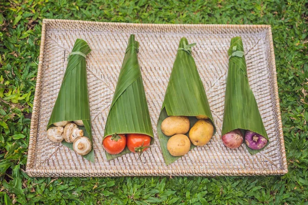 Concepto de envasado de productos ecológicos. Verduras envueltas en una hoja de plátano, como alternativa a una bolsa de plástico. Concepto de cero residuos. Envases alternativos —  Fotos de Stock