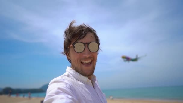 Superslowmotion tiro de un turista feliz divertirse en una playa tropical con un avión volando sobre él — Vídeos de Stock