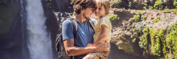 Papà e figlio turisti sullo sfondo di una cascata. Viaggiare con il concetto di bambini. Cosa fare con i bambini Luogo adatto ai bambini BANNER, FORMATO LUNGO — Foto Stock