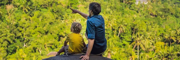 Dad and son tourists on a stone over the jungle. Traveling with kids concept. What to do with children. Child friendly place BANNER, LONG FORMAT