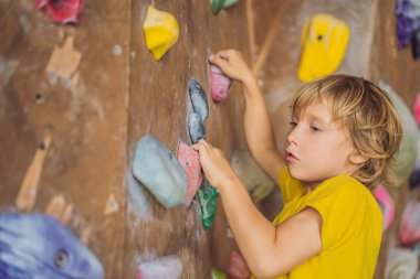 Küçük çocuk özel botlar içinde bir kaya duvarına tırmanıyor. Kapalı