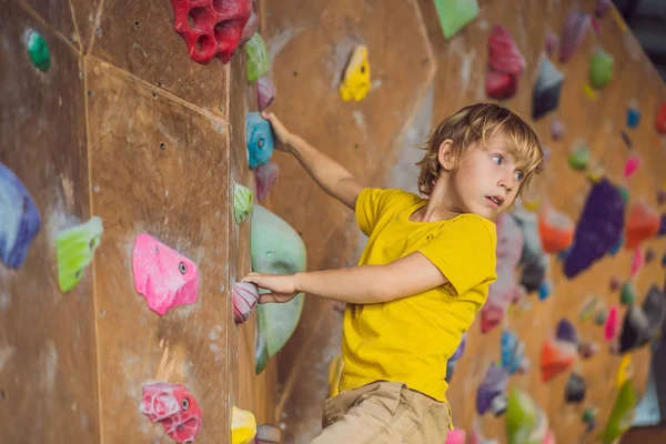 Niño pequeño escalando una pared de roca con botas especiales. interior — Foto de Stock