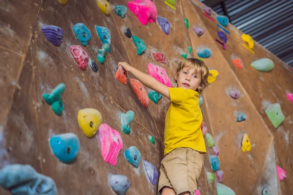 Niño pequeño escalando una pared de roca con botas especiales. interior — Foto de Stock