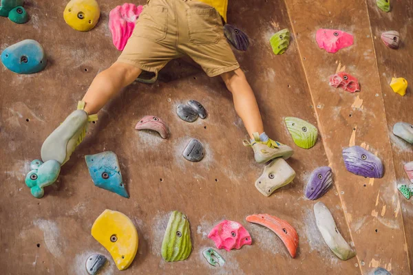 Niño pequeño escalando una pared de roca con botas especiales. interior — Foto de Stock