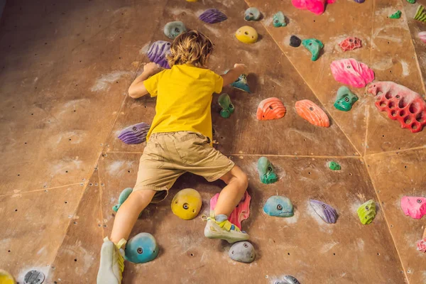 Niño pequeño escalando una pared de roca con botas especiales. interior — Foto de Stock