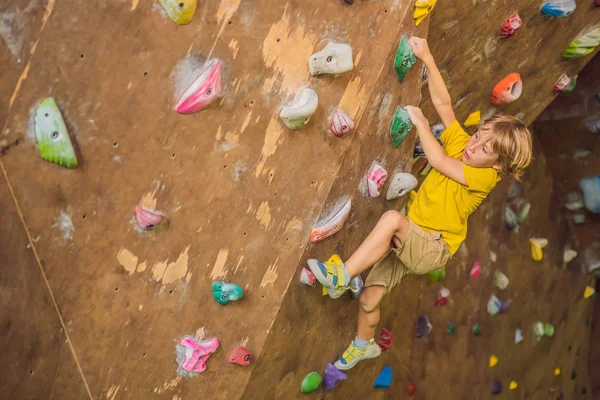 Rapazinho a escalar uma parede de pedra com botas especiais. interior — Fotografia de Stock