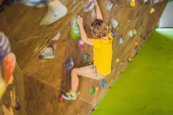 Niño pequeño escalando una pared de roca con botas especiales. interior —  Fotos de Stock