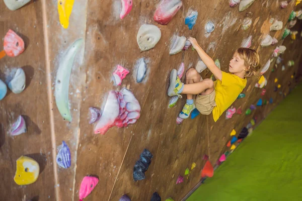 Niño pequeño escalando una pared de roca con botas especiales. interior — Foto de Stock