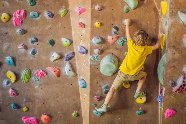 Niño pequeño escalando una pared de roca con botas especiales. interior — Foto de Stock