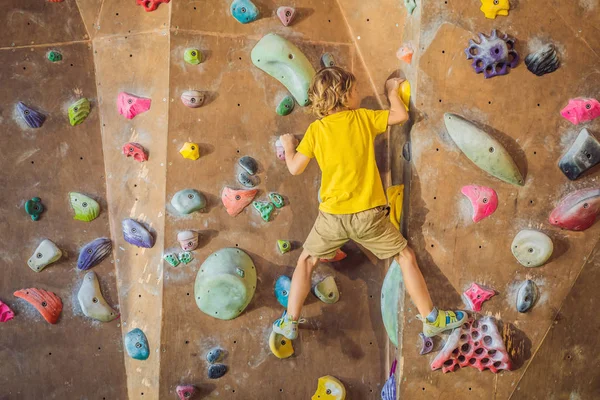 Niño pequeño escalando una pared de roca con botas especiales. interior — Foto de Stock