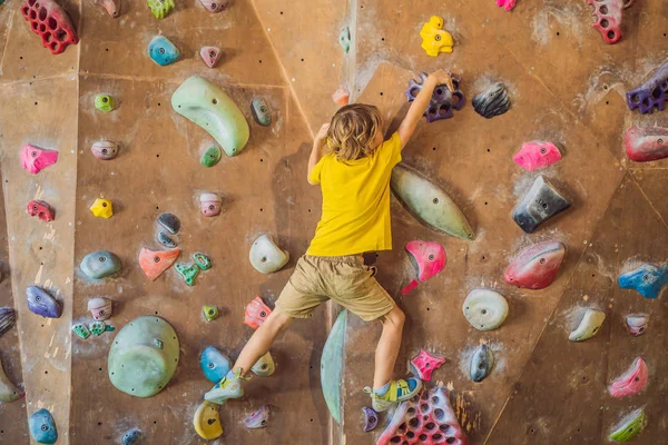 Niño pequeño escalando una pared de roca con botas especiales. interior —  Fotos de Stock