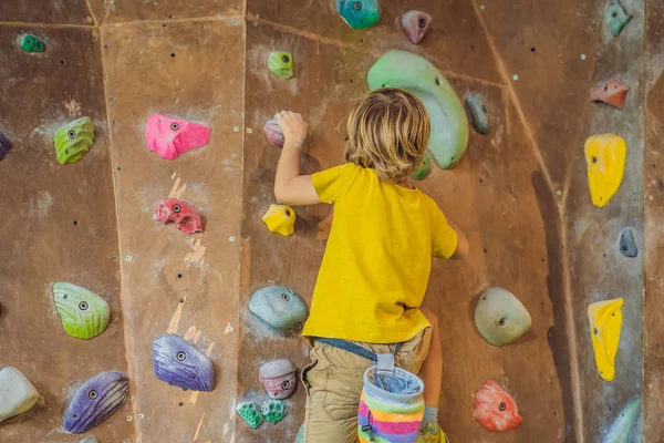 Rapazinho a escalar uma parede de pedra com botas especiais. interior — Fotografia de Stock