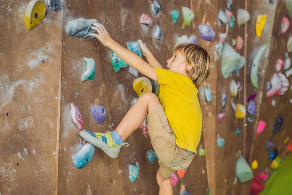 Niño pequeño escalando una pared de roca con botas especiales. interior — Foto de Stock