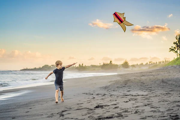 Gelukkige jongen vliegen vlieger op het strand bij zonsondergang — Stockfoto