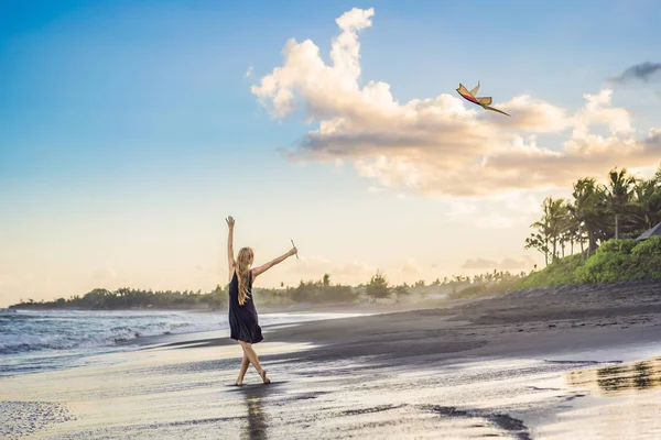 Una giovane donna lancia un aquilone sulla spiaggia. Sogno, aspirazioni, progetti futuri — Foto Stock