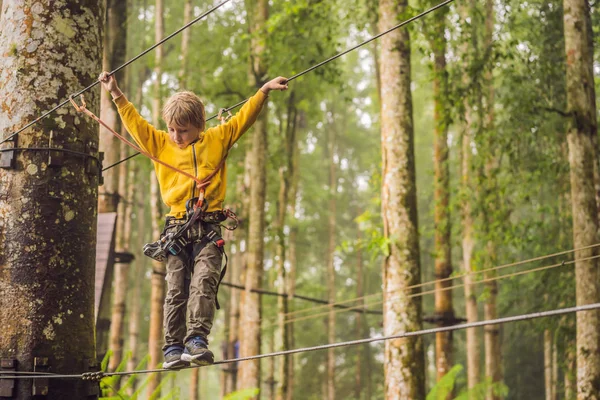 Kleine jongen in een touwenpark. Actieve fysieke recreatie van het kind in de frisse lucht in het park. Opleiding voor kinderen — Stockfoto