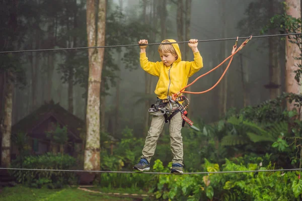 Un ragazzino in un parco di corde. Ricreazione fisica attiva del bambino all'aria aperta nel parco. Formazione per bambini — Foto Stock