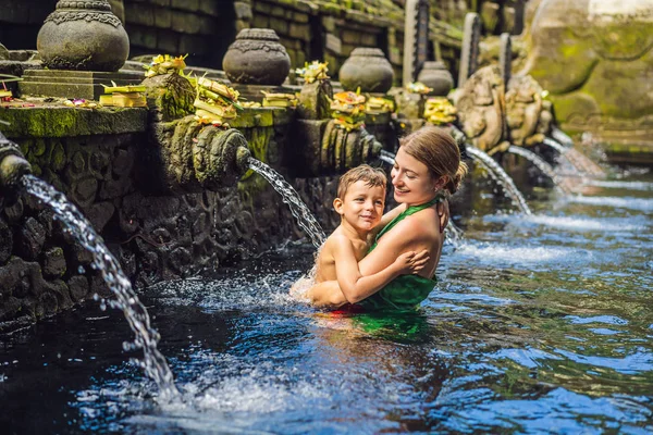 Mãe e filho em templo de água benta em bali. O composto do templo consiste em uma estrutura petirtaan ou de banho, famosa para sua água benta da mola — Fotografia de Stock