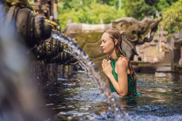Frau im Tempel des heiligen Quellwassers in Bali. Die Tempelanlage besteht aus einer Petirtaan oder Badestruktur, die für ihr heiliges Quellwasser berühmt ist — Stockfoto