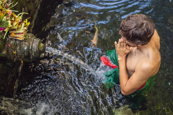 Man in holy spring water temple in bali. The temple compound consists of a petirtaan or bathing structure, famous for its holy spring water