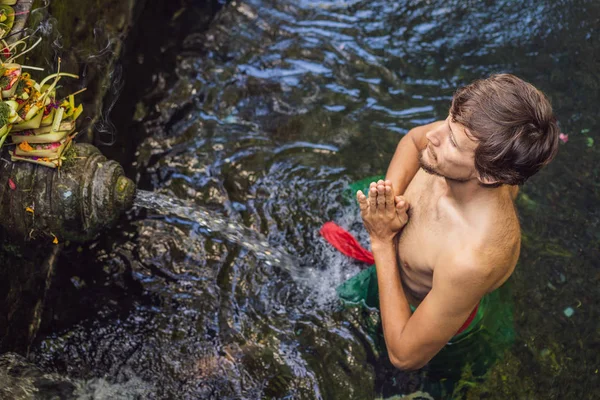 Man in de Heilige lente water tempel in Bali. De tempel compound bestaat uit een petirtaan of zwem structuur, beroemd om zijn heilige bronwater — Stockfoto