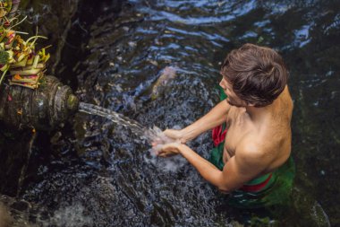 Bali 'de kutsal bahar su tapınağında adam. Tapınak bileşiği, kutsal kaynak suyu ile ünlü bir petirtaan veya banyo yapısından oluşur.