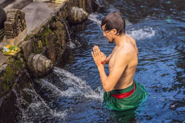 Bali 'de kutsal bahar su tapınağında adam. Tapınak bileşiği, kutsal kaynak suyu ile ünlü bir petirtaan veya banyo yapısından oluşur.