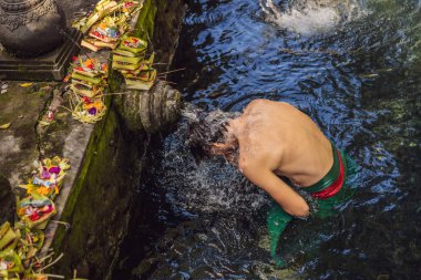 Bali 'de kutsal bahar su tapınağında adam. Tapınak bileşiği, kutsal kaynak suyu ile ünlü bir petirtaan veya banyo yapısından oluşur.