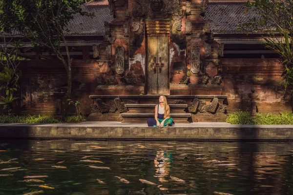 Woman feeding beautiful coloured fish in pond temple on Bali — Stock Photo, Image