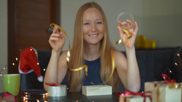 Genç bir kadının Slowmotion çekimi hediyeler topluyor. Present yılbaşı veya yeni yıl için kırmızı ve altın kurdele ile Craft kağıt sarılmış. Kadın çocukları için bir geliş takvimi yapar — Stok video