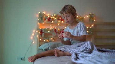 Slowmotion Noel ışıkları ile aydınlatılmış bir yatakta asılı bir geliş takvimden bir hediye açılış küçük bir çocuk vurdu. Noel ve yeni yıl konsepti için hazırlanıyor. Advent