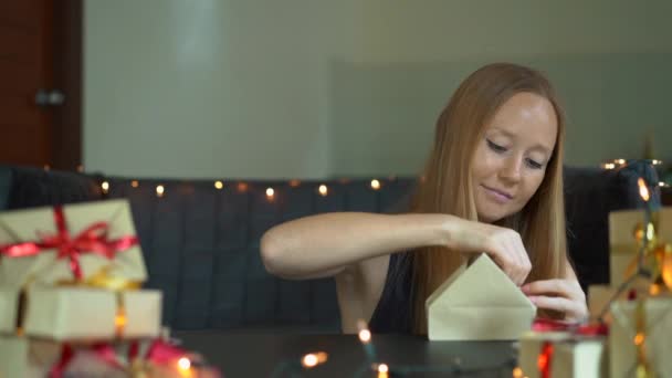 Slowmotion shot van een jonge vrouw is verpakking presenteert. Aanwezig verpakt in ambachtelijke papier met een rood en goud lint voor Kerstmis of Nieuwjaar. Vrouw maakt een adventkalender voor haar kinderen — Stockvideo