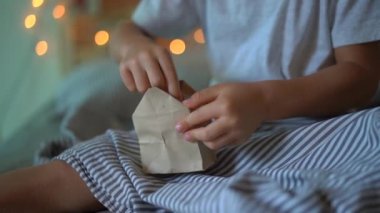 Slowmotion Noel ışıkları ile aydınlatılmış bir yatakta asılı bir geliş takvimden bir hediye açılış küçük bir çocuk vurdu. Noel ve yeni yıl konsepti için hazırlanıyor. Advent