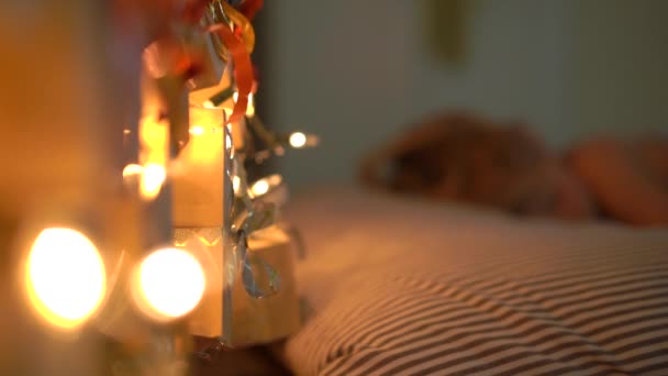 Filmagem em câmera lenta de um menino dormindo em sua cama com um calendário de advento iluminar com luzes de Natal brilha em uma parte de trás de sua cama. Preparando-se para o Natal e Ano Novo conceito. Calendário do Advento — Vídeo de Stock