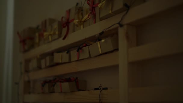 Zeitlupenaufnahme eines Adventskalenders, der an einem Bett hängt, das mit Weihnachtslichtern beleuchtet ist. Wir bereiten uns auf Weihnachten und Neujahr vor. Adventskalender-Konzept — Stockvideo