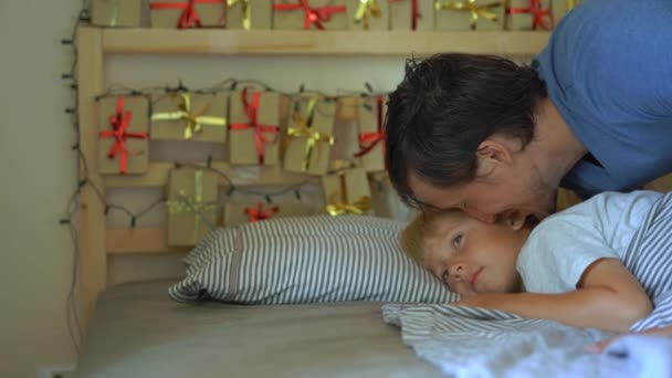 Медленная съемка разбудила его маленького сына. Он будит мальчика и показывает ему рождественский календарь, который он сделал сам. Готовимся к Рождеству и Новому году. Адвентный календарь — стоковое видео