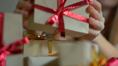 Hediyeler paketlemeye yarayan genç bir kadın. Present yılbaşı veya yeni yıl için kırmızı ve altın kurdele ile Craft kağıt sarılmış. Kadın çocukları için bir geliş takvimi yapar