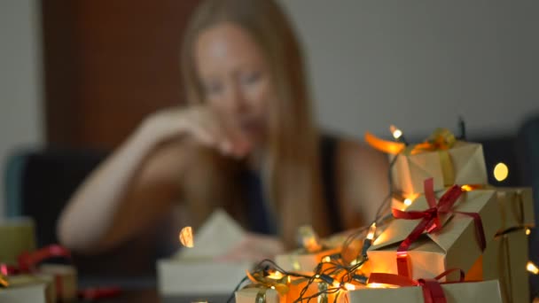 Een jonge vrouw Pack presenteert. Ze is moe van het maken van zo veel cadeaus voor grote feestdagen. Het concept van vermoeidheid van de kerst en Nieuwjaar — Stockvideo