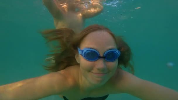 Slowmotion tiro subaquático de uma mulher e seu pequeno filho se divertindo em um mar azul — Vídeo de Stock