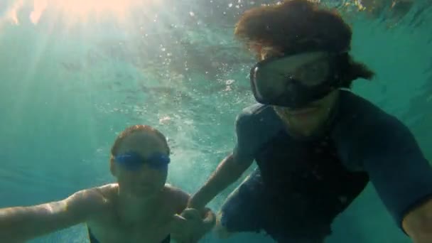 Captura submarina en cámara lenta de una feliz pareja de mujeres y hombres buceando en una piscina. Vida sana, personas activas — Vídeo de stock