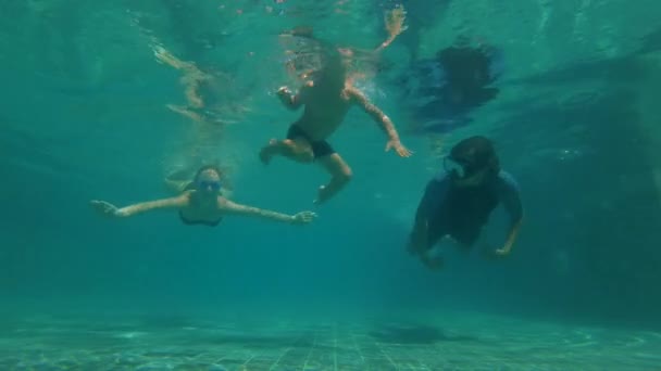 Медленная подводная съемка счастливой семьи, ныряющей в бассейн. Здоровый образ жизни, активные родители — стоковое видео